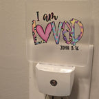 Frosted acrylic night light with a colorful heart and leopard print "I am Loved, John 3:16" design, plugged into a wall outlet