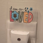 Frosted acrylic night light with a floral "I am so Loved, John 3:16" design, plugged into a wall outlet