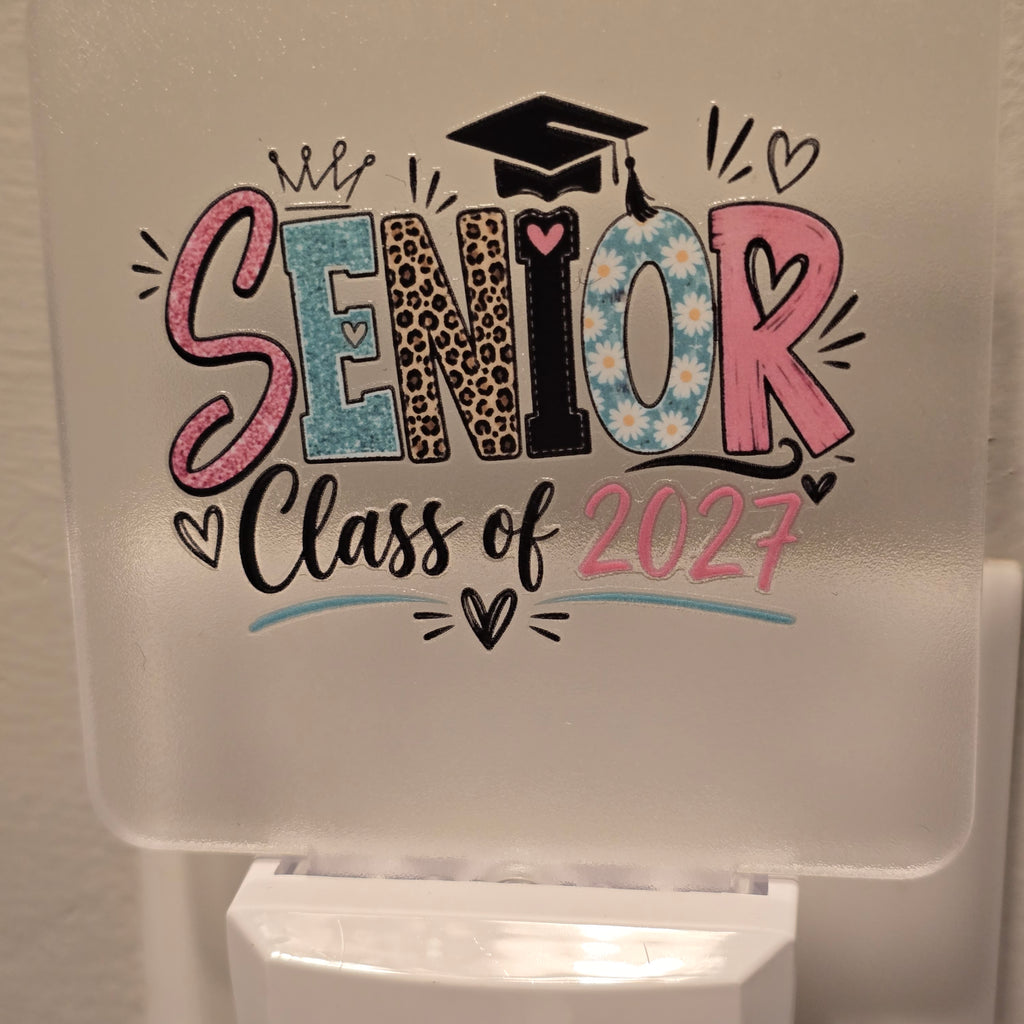Frosted acrylic night light with a colorful "Senior Class of 2027" design, plugged into a wall outlet