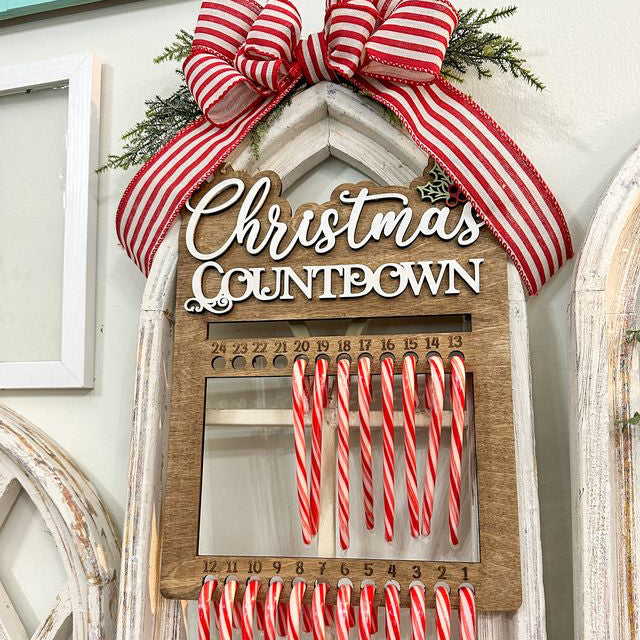 Christmas countdown calendar with candy canes and a large bow on a decorative wall.