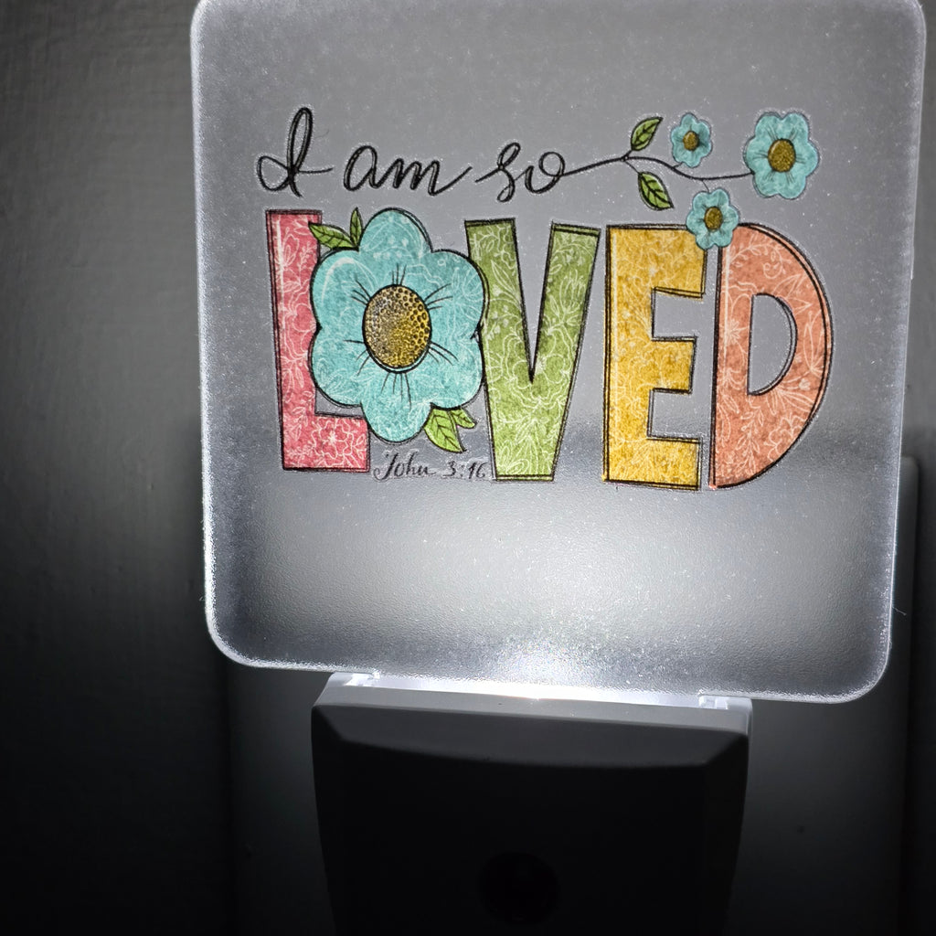 Frosted acrylic night light with a floral "I am so Loved, John 3:16" design, glowing in a dark room