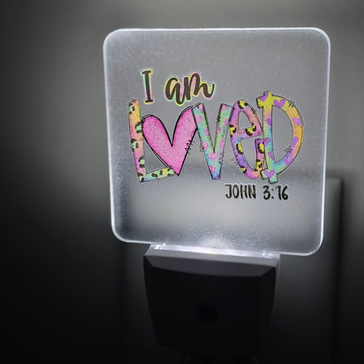 Frosted acrylic night light with a colorful heart and leopard print "I am Loved, John 3:16" design, glowing in a dark room