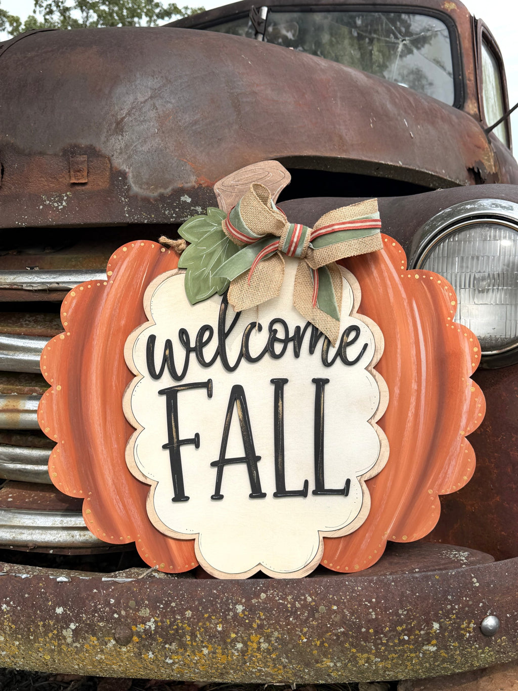 Welcome Fall pumpkin door hanger with sage leaf and fall ribbon bow on a vintage rusty truck, cut by Rise and Shine Gifts in Dothan, Alabama - SHINE-DH-011