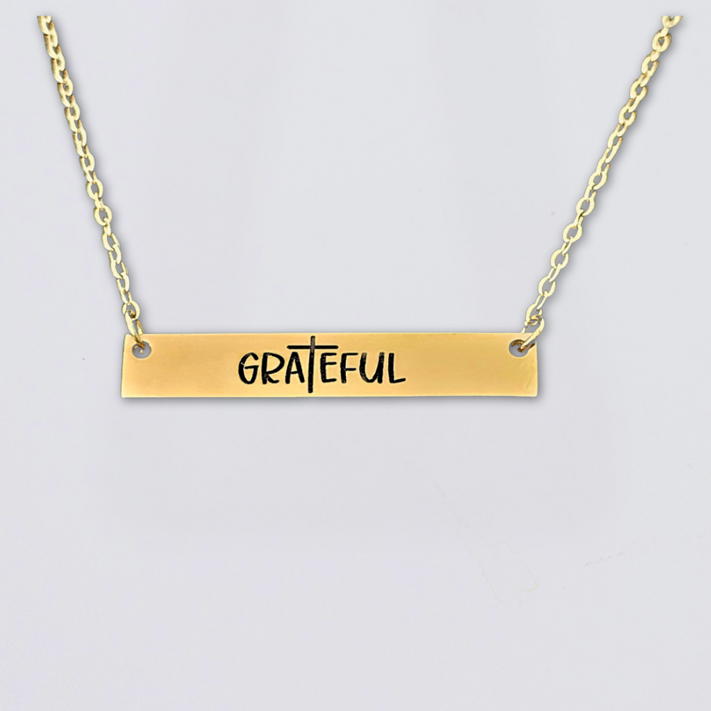 A collection of stainless steel bar necklaces with different motivational words engraved on them, displayed in silver, gold plated, and rose gold colors.