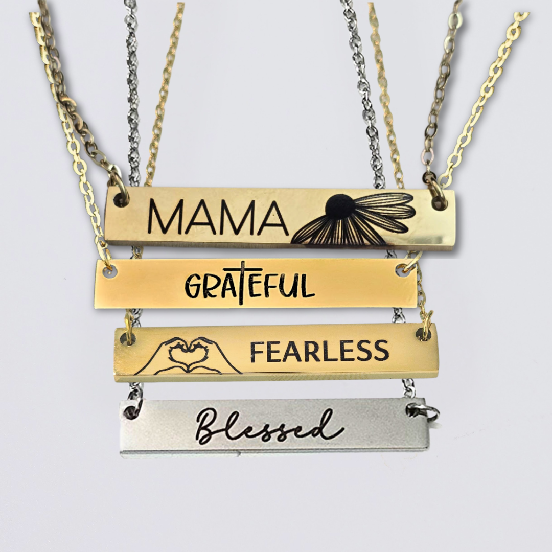 A collection of stainless steel bar necklaces with different motivational words engraved on them, displayed in silver, gold plated, and rose gold colors.